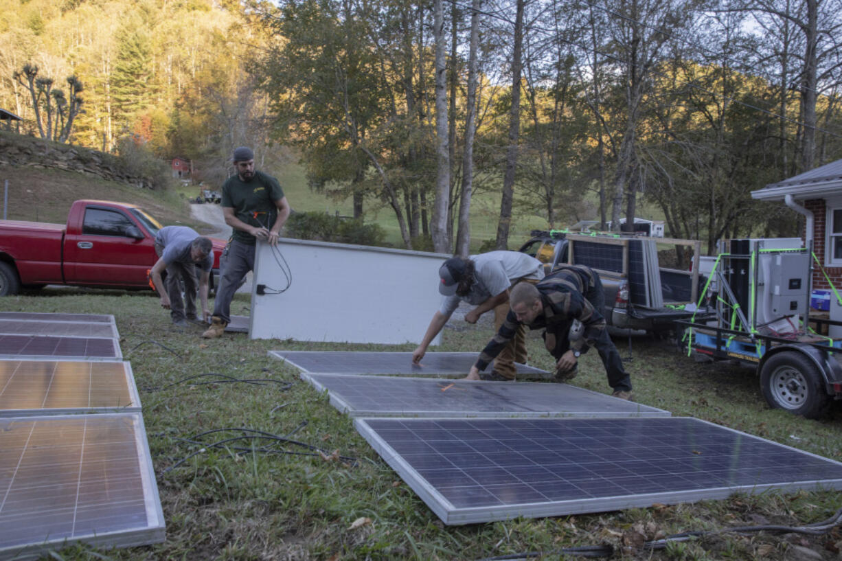 Hayden Wilson, left, Alexander Pellersels, second from left, Jonathan Bowen and Henry Kovacs, right, install a mobile power system at the Beans Creek Church of the Lord Jesus Christ in Bakersville, N.C. on Oct. 9, 2024.