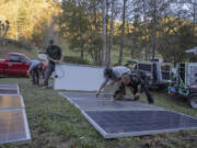 Hayden Wilson, left, Alexander Pellersels, second from left, Jonathan Bowen and Henry Kovacs, right, install a mobile power system at the Beans Creek Church of the Lord Jesus Christ in Bakersville, N.C. on Oct. 9, 2024.