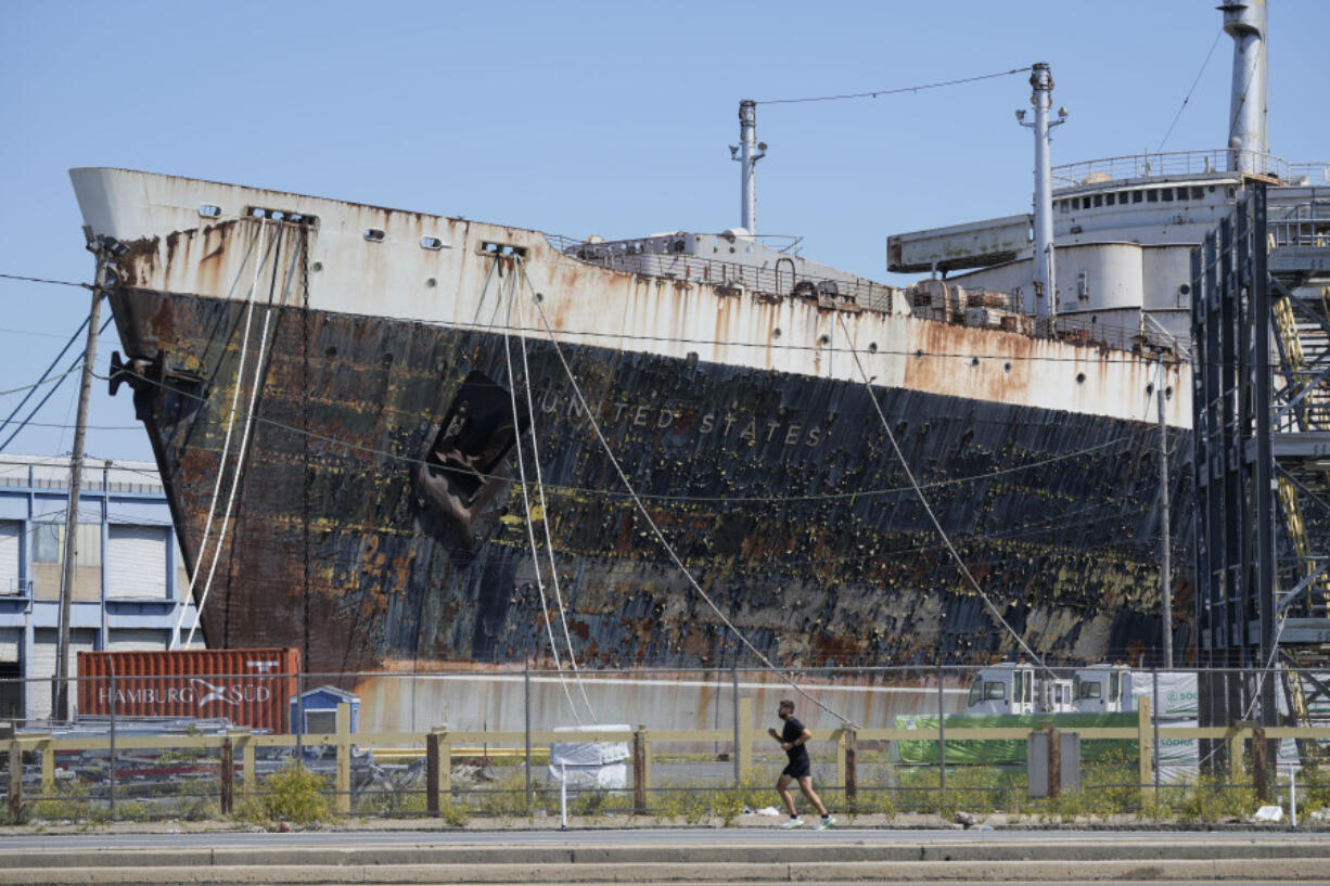 FILE - A person runs past the S.S. United States moored on the Delaware River in Philadelphia, Sept. 4, 2024.