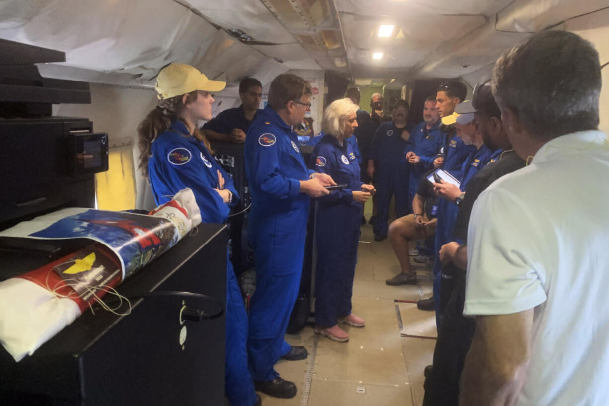 In this image released by the National Oceanic and Atmospheric Administration, a NOAA crew on a reconnaissance flight, Tuesday, Oct. 8, 2024, into the eye of Hurricane Milton in the Gulf of Mexico, gather before dropping a package containing the ashes of Peter Dodge, an award-winning scientist who made almost 400 hundreds flight into the eyes of hurricanes, as a lasting tribute to the longtime radar specialist and researcher.