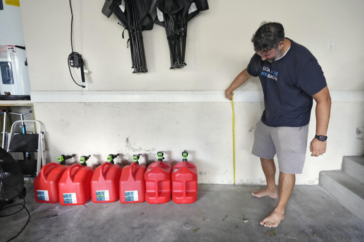 Chris Sundar measures the depth of floodwaters from Hurricane Milton in his garage Sunday, Oct. 13, 2024, in Tampa, Fla.