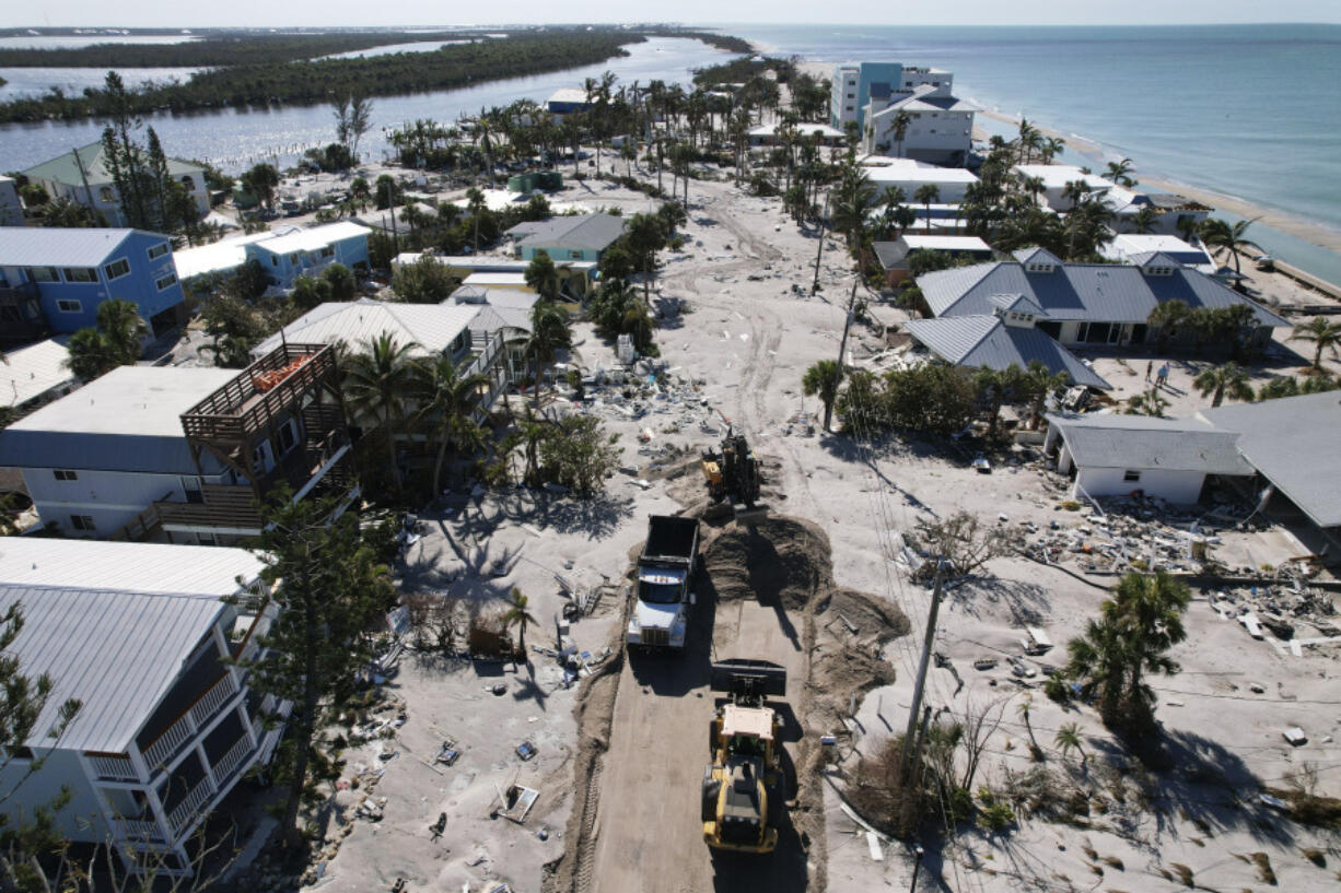 Charlotte County workers clear feet of sand from a road on southern Manasota Key, in Englewood, Fla., following the passage of Hurricane Milton, Sunday, Oct. 13, 2024.