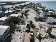 Charlotte County workers clear feet of sand from a road on southern Manasota Key, in Englewood, Fla., following the passage of Hurricane Milton, Sunday, Oct. 13, 2024.