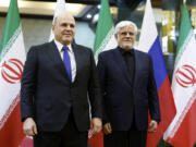 Russian Prime Minister Mikhail Mishustin, left, and Iranian First Vice President Mohammad Reza Aref pose for photos before a meeting in Tehran, Iran, Monday, Sept. 30, 2024.