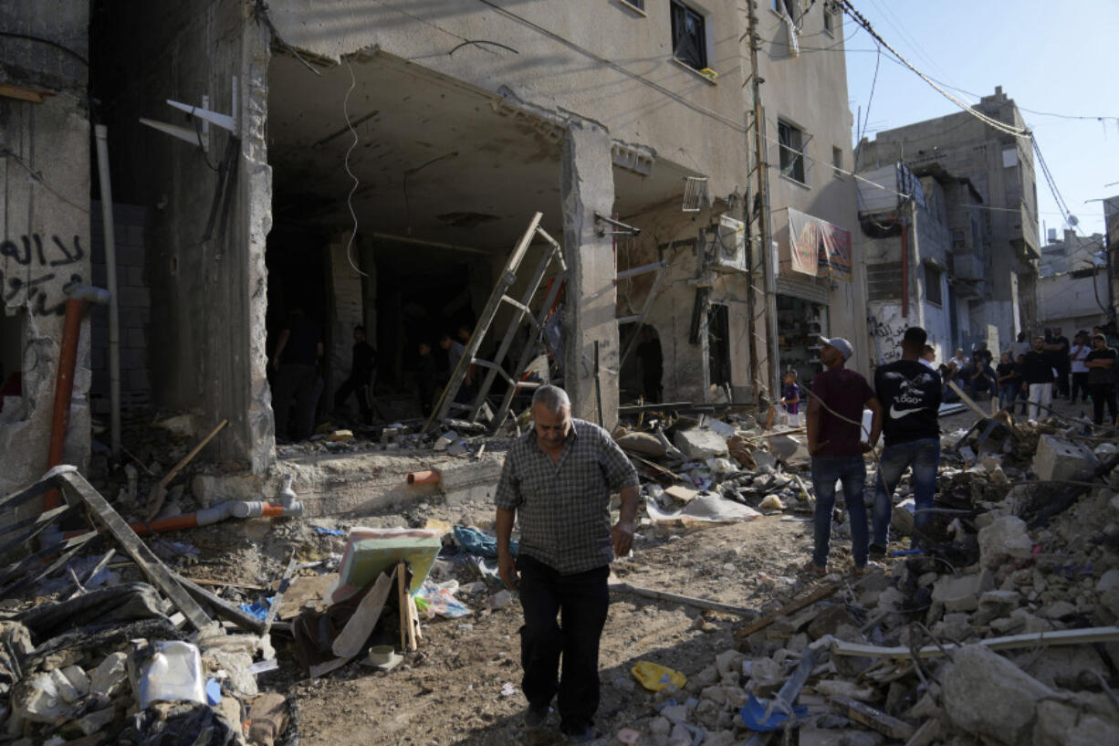 Palestinians examine the damage following an Israeli airstrike in the West Bank city of Tulkarem, which Palestinian health officials say killed 18 people and the Israeli military says took out a Hamas leader, on Friday, Oct. 4, 2024.