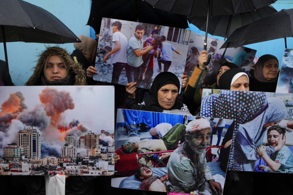 FILE - Palestinian Hamas supporters hold posters shows the Israeli bombardment on Gaza during a protest demanding that staff who were fired in the Gaza Strip over allegations that they took part in the Oct. 7, attack on southern Israel be returned to their jobs and that countries resume funding of the agency, in front of the United Nations Relief and Works Agency (UNRWA) headquarters in Beirut, Tuesday, Jan. 30, 2024.