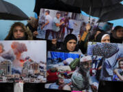 FILE - Palestinian Hamas supporters hold posters shows the Israeli bombardment on Gaza during a protest demanding that staff who were fired in the Gaza Strip over allegations that they took part in the Oct. 7, attack on southern Israel be returned to their jobs and that countries resume funding of the agency, in front of the United Nations Relief and Works Agency (UNRWA) headquarters in Beirut, Tuesday, Jan. 30, 2024.