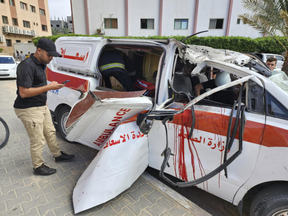 FILE - Palestinian medics inspect a damaged Ambulance hit by an Israeli air strike inside Nasser Hospital in Khan Younis, southern Gaza Strip, Saturday, Oct. 7, 2023.