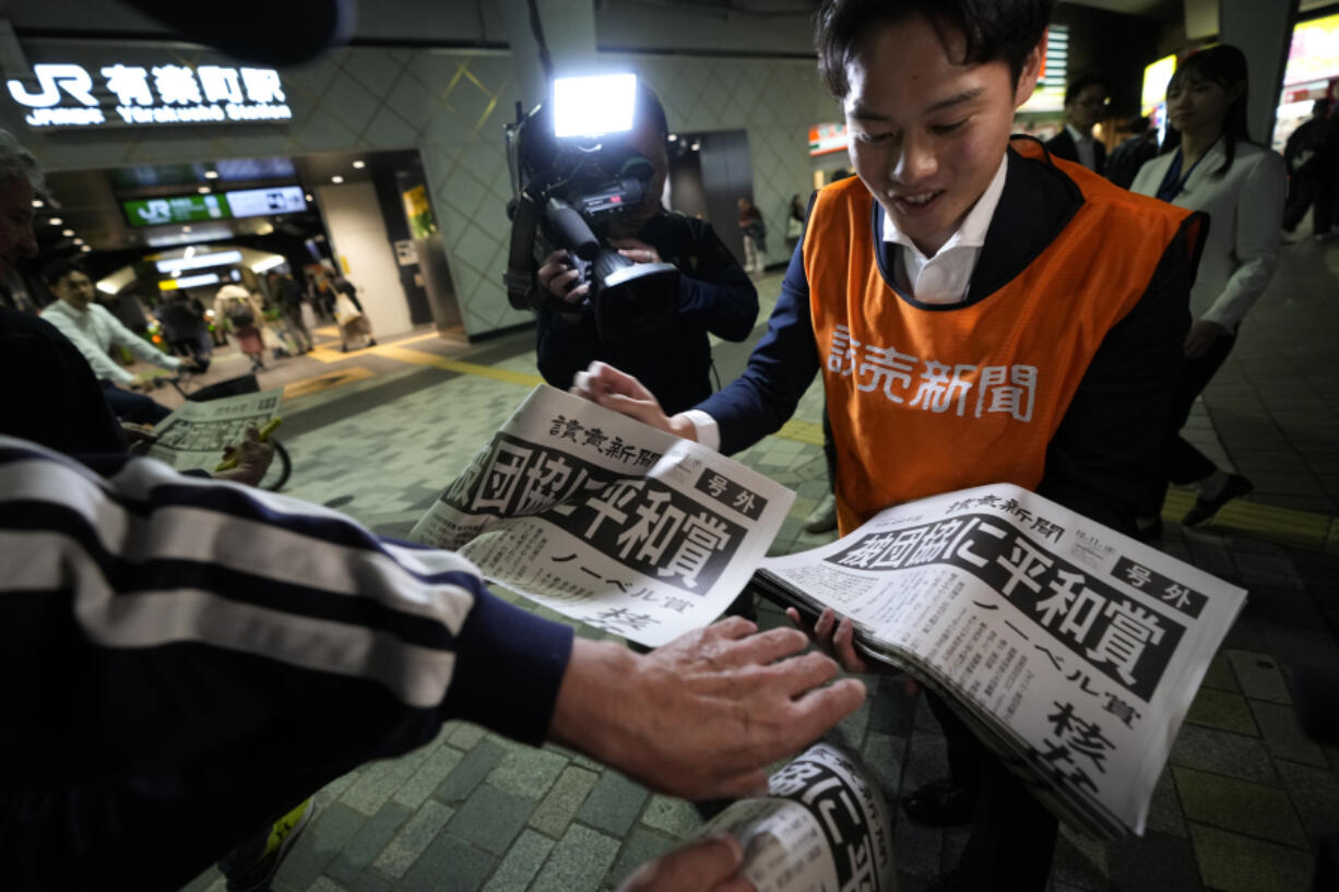 A worker of the Yomiuri Shimbun newspaper hands out copies of an extra version to passersby in Tokyo, Friday, Oct. 11, 2024, after Nihon Hidankyo, or the Japan Confederation of A- and H-Bomb Sufferers Organizations, won the Nobel Peace Prize.