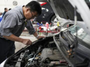 Auto mechanic Willie Chung works on a vehicle at the Express Auto Service Inc., in Chicago, Thursday, Sept. 19, 2024. (AP Photo/Nam Y.