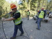 FILE - Carl Roath, left, a worker with the Mason County (Wash.) Public Utility District, pulls fiber optic cable on a project to install broadband internet service in the area surrounding Lake Christine near Belfair, Wash., on Aug. 4, 2021. (AP Photo/Ted S.