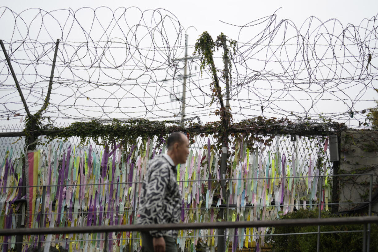 A visitor walks near a wire fence decorated with ribbons written with messages wishing for the reunification of the two Koreas at the Imjingak Pavilion in Paju, South Korea, Tuesday, Oct. 15, 2024.