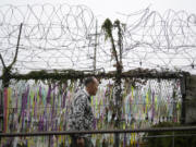 A visitor walks near a wire fence decorated with ribbons written with messages wishing for the reunification of the two Koreas at the Imjingak Pavilion in Paju, South Korea, Tuesday, Oct. 15, 2024.