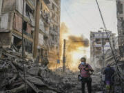 A photographer runs for cover as a smoke raises in the background following an Israeli airstrike in Dahiyeh, Beirut, Lebanon, Friday, Oct. 4, 2024.