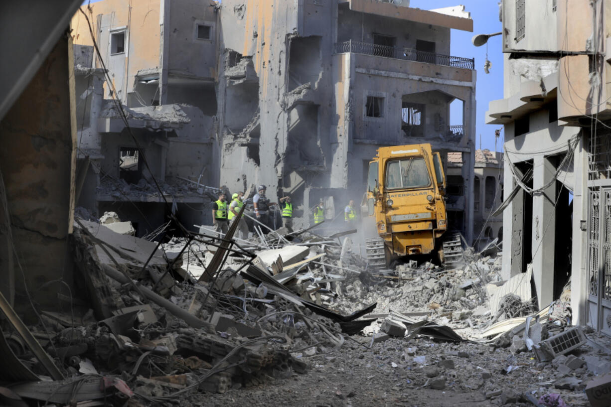 Rescue workers use a bulldozer to remove rubble of destroyed buildings, as they search for victims at the site that was hit by Israeli airstrikes in Qana village, south Lebanon, Wednesday, Oct. 16, 2024.