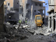 Rescue workers use a bulldozer to remove rubble of destroyed buildings, as they search for victims at the site that was hit by Israeli airstrikes in Qana village, south Lebanon, Wednesday, Oct. 16, 2024.