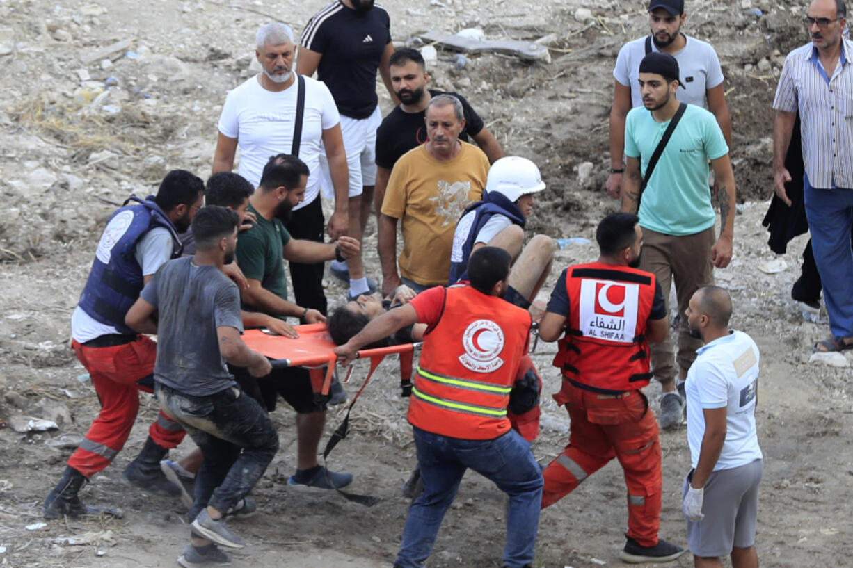 Rescue workers carry a man who was injured after an Israeli airstrike hit two adjacent buildings, in Ain el-Delb neighbourhood east of the southern port city of Sidon, Lebanon, Sunday, Sept. 29, 2024.