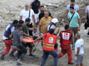 Rescue workers carry a man who was injured after an Israeli airstrike hit two adjacent buildings, in Ain el-Delb neighbourhood east of the southern port city of Sidon, Lebanon, Sunday, Sept. 29, 2024.