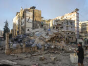 A man documents the damaged buildings at the site of an Israeli airstrike in Dahiyeh, Beirut, Lebanon, Friday, Oct. 4, 2024.