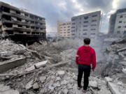 FILE - A man looks at destroyed buildings hit by Israeli airstrikes in Dahiyeh, Beirut, Lebanon, Monday, Oct. 7, 2024. Now in Lebanon, the Israeli military tells residents that they live near &ldquo;facilities and interests&rdquo; belonging to the militant Hezbollah group that they will strike soon. These warnings often come ahead of a series of overnight strikes on buildings in the Beirut southern suburbs, though there often are far more strikes than warned about.