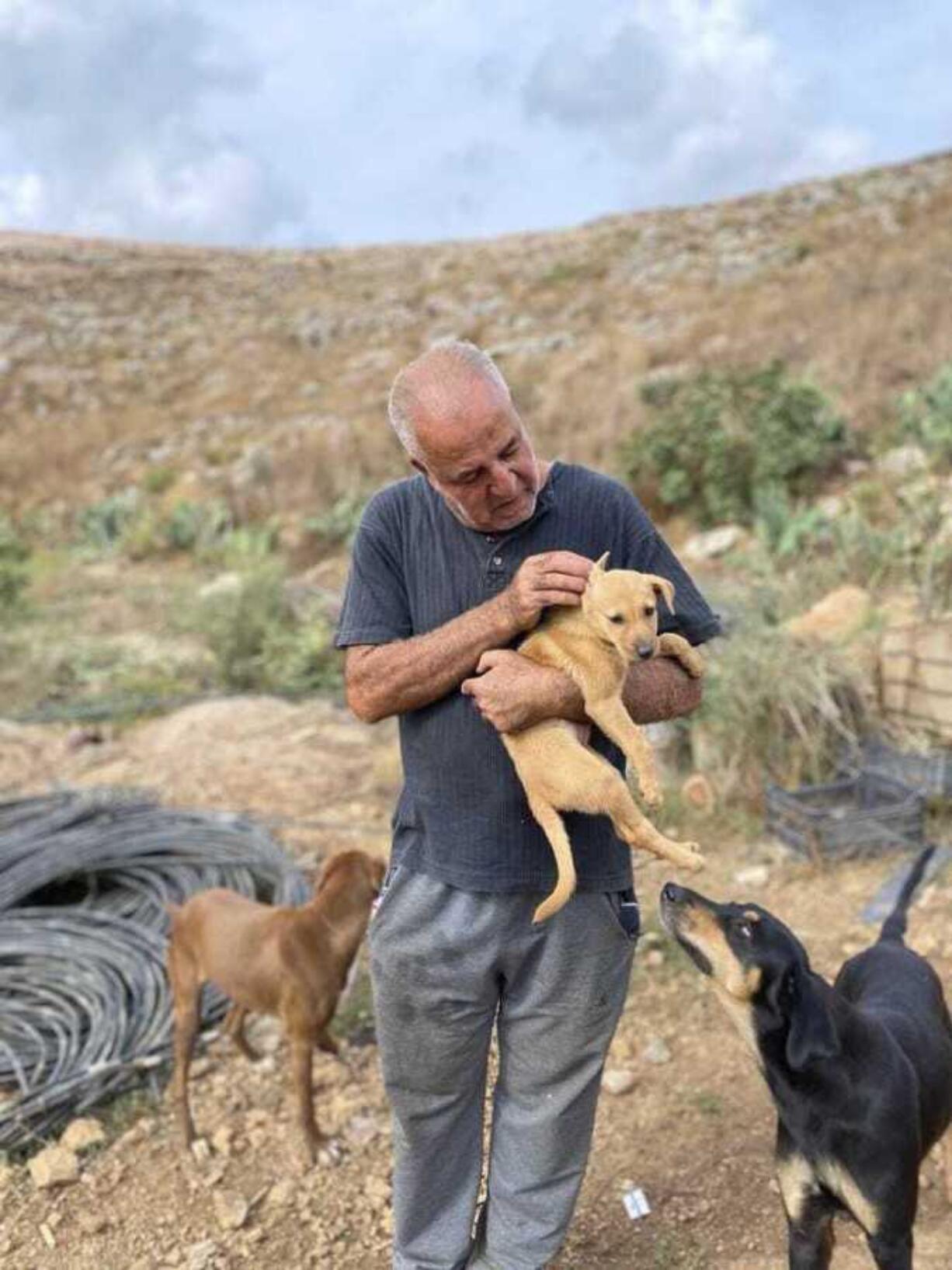 In this photo provided by Mashala Shelter, Hussein Hamza carries a puppy at his animal shelter in Kfour, south Lebanon in 2024.