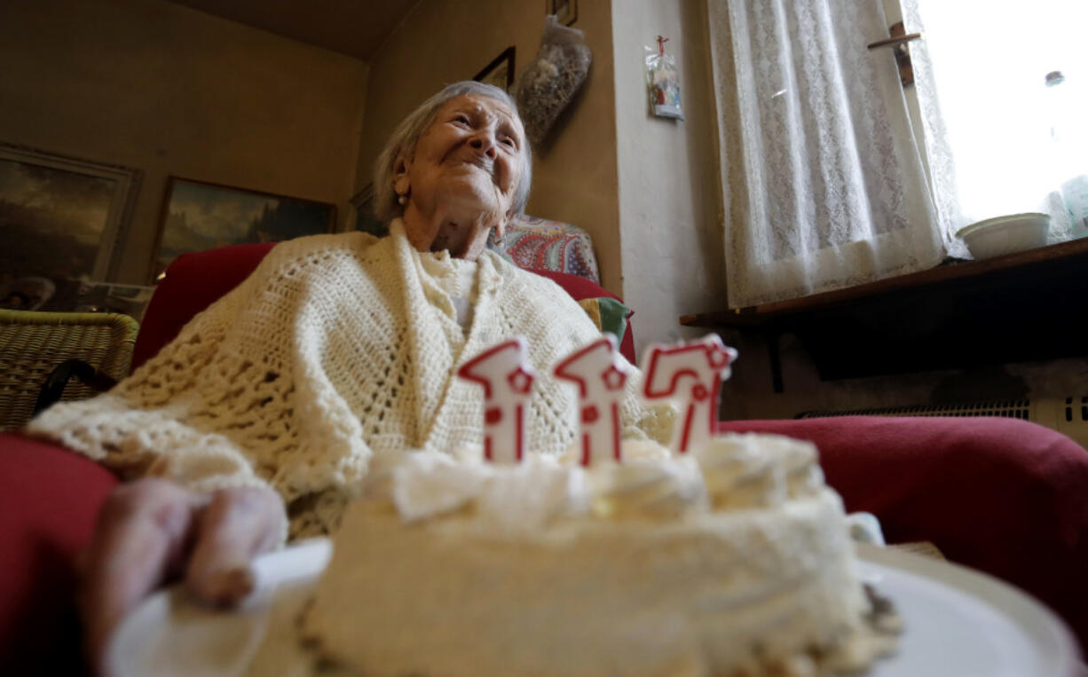 FILE- Emma Morano holds a cake with candles marking 117 years on the day of her birthday, Nov. 29, 2016, in Verbania, Italy.