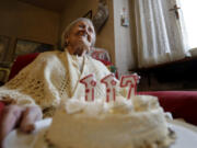 FILE- Emma Morano holds a cake with candles marking 117 years on the day of her birthday, Nov. 29, 2016, in Verbania, Italy.