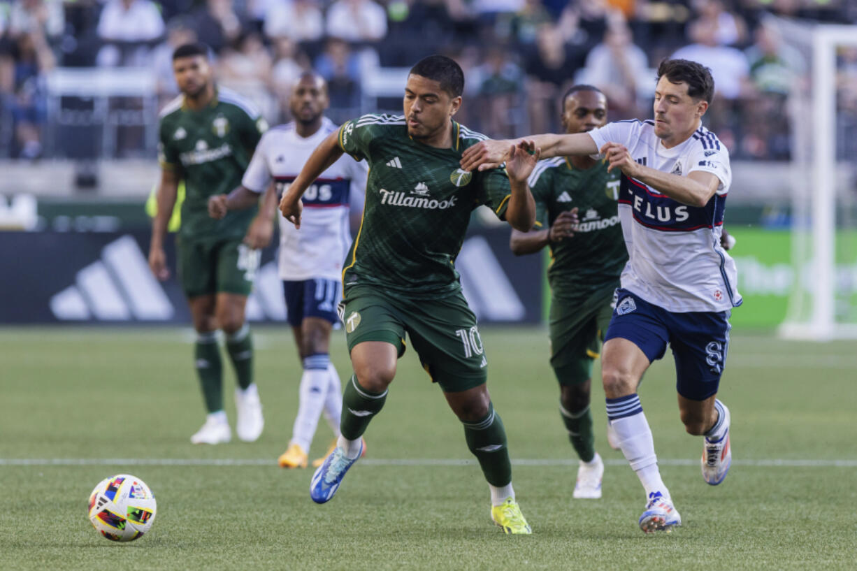 FILE - Portland Timbers midfielder Evander (10) an Vancouver Whitecaps midfielder Alessandro Sch&ouml;pf (8) vie for the ball during an MLS soccer match, June 22, 2024, in Portland, Ore.