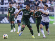 FILE - Portland Timbers midfielder Evander (10) an Vancouver Whitecaps midfielder Alessandro Sch&ouml;pf (8) vie for the ball during an MLS soccer match, June 22, 2024, in Portland, Ore.