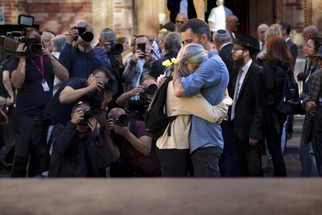 Rotem gets a hug from her husband Yoav after a commemoration marking one year since the Hamas attacks in Israel at the Coral Temple Synagogue, Monday, Oct. 7, 2024, in Bucharest, Romania.