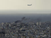 A Middle East Airlines airplane flies over Beirut as smoke rises from Israeli airstrikes in Dahiyeh, Beirut, Tuesday, Oct. 1, 2024.