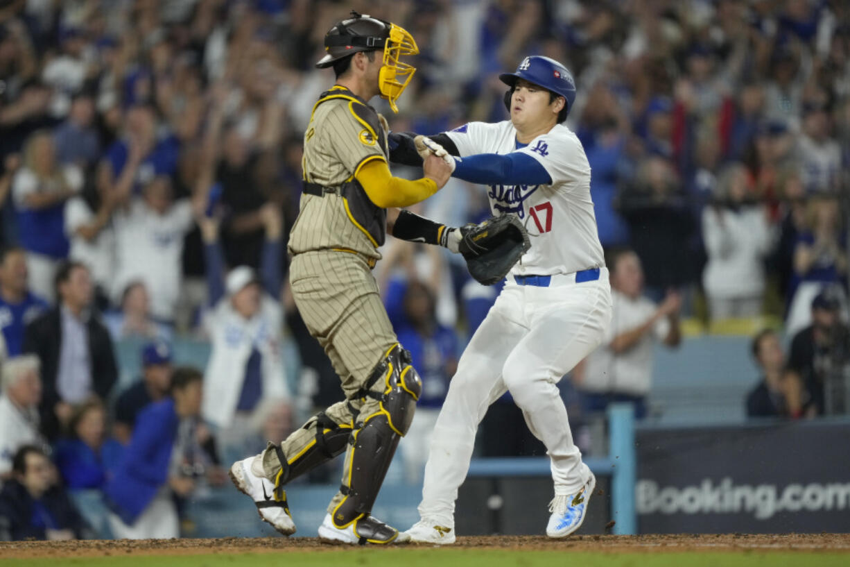 Los Angeles Dodgers&#039; Shohei Ohtani, right, collides with San Diego Padres catcher Kyle Higashioka as he scores on a single by Teoscar Hern&aacute;ndez during the fourth inning in Game 1 of baseball&#039;s NL Division Series Saturday, Oct. 5, 2024, in Los Angeles. (AP Photo/Mark J.