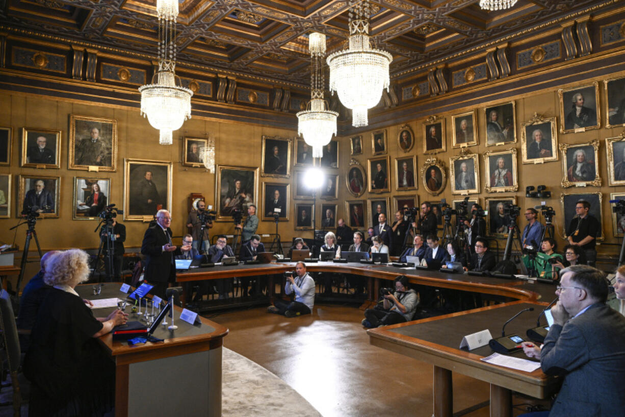 FILE - Mats Larsson, member of the Royal Academy of Sciences, standing at left, speaks during the announcement of the winner of the 2023 Nobel Prize in Physics, at the Royal Academy of Sciences, in Stockholm, on Oct. 3, 2023.