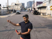 FILE - Vivek Shandas, a professor of climate adaptation at Portland State University, takes a temperature reading of almost 106 degrees in downtown Portland, Ore., Aug. 12, 2021.