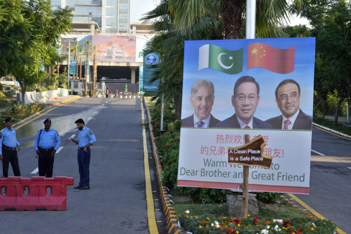 Police officers stand guard next to a welcoming billboard with portraits of China&rsquo;s Premier Li Qiang, center, Pakistan&rsquo;s Prime Minister Shehbaz Sharif and President Asif Ali Zardari, displayed at a road leading to the venue of the upcoming Shanghai Cooperation Organization (SCO) summit in Islamabad, Pakistan, Sunday, Oct. 13, 2024.