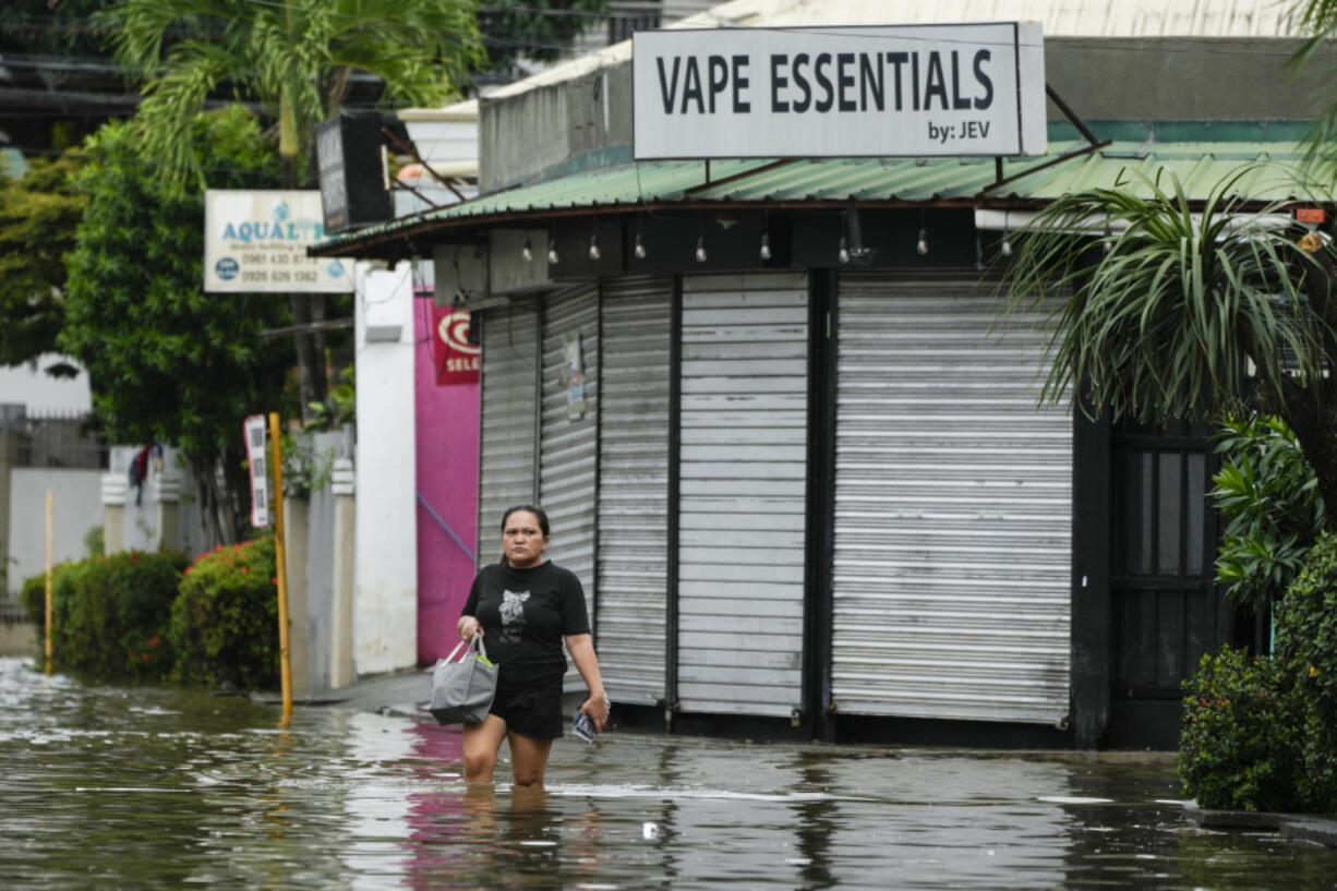 A resident crosses flooded streets caused by Tropical Storm Trami on Friday, Oct. 25, 2024, in Cainta, Rizal province, Philippines.