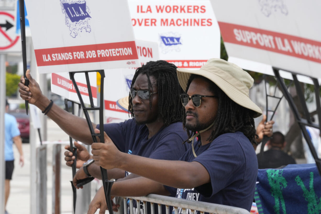 Dockworkers from Port Miami display signs at a picket line, Thursday, Oct. 3, 2024, in Miami.