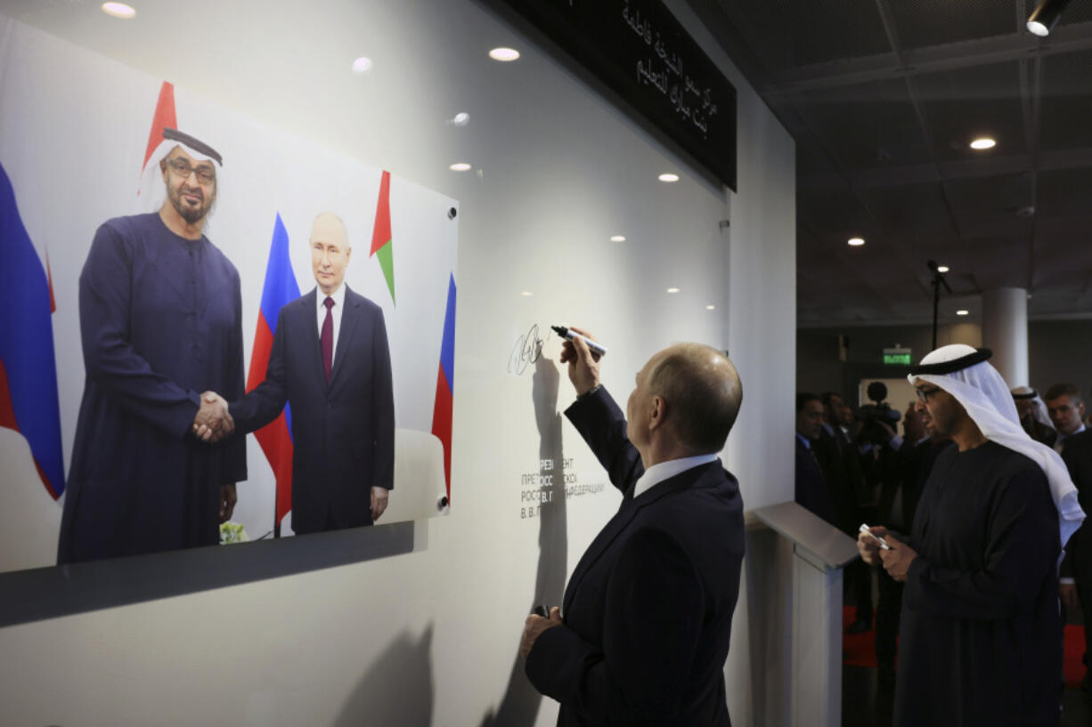 Russian President Vladimir Putin, left, and United Arab Emirates President Sheikh Mohammed bin Zayed Al Nahyan sign a wall at newly opened Sheikha Fatima bint Mubarak Education Center at Primakov School in Moscow, Russia, Monday, Oct. 21, 2024.