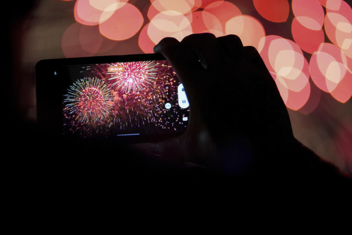 FILE - A spectator records a cell phone video as fireworks are launched over the Ohio River during the Western &amp; Southern WEBN Fireworks show in Cincinnati on Sept. 3, 2023, in Cincinnati.