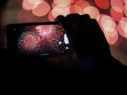 FILE - A spectator records a cell phone video as fireworks are launched over the Ohio River during the Western &amp; Southern WEBN Fireworks show in Cincinnati on Sept. 3, 2023, in Cincinnati.