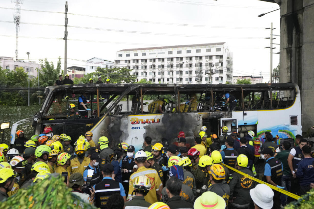 Rescuer inspect a bus which caught fire as it was carrying young students with their teachers, in suburban Bangkok, Tuesday, Oct. 1, 2024.