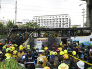 Rescuer inspect a bus which caught fire as it was carrying young students with their teachers, in suburban Bangkok, Tuesday, Oct. 1, 2024.