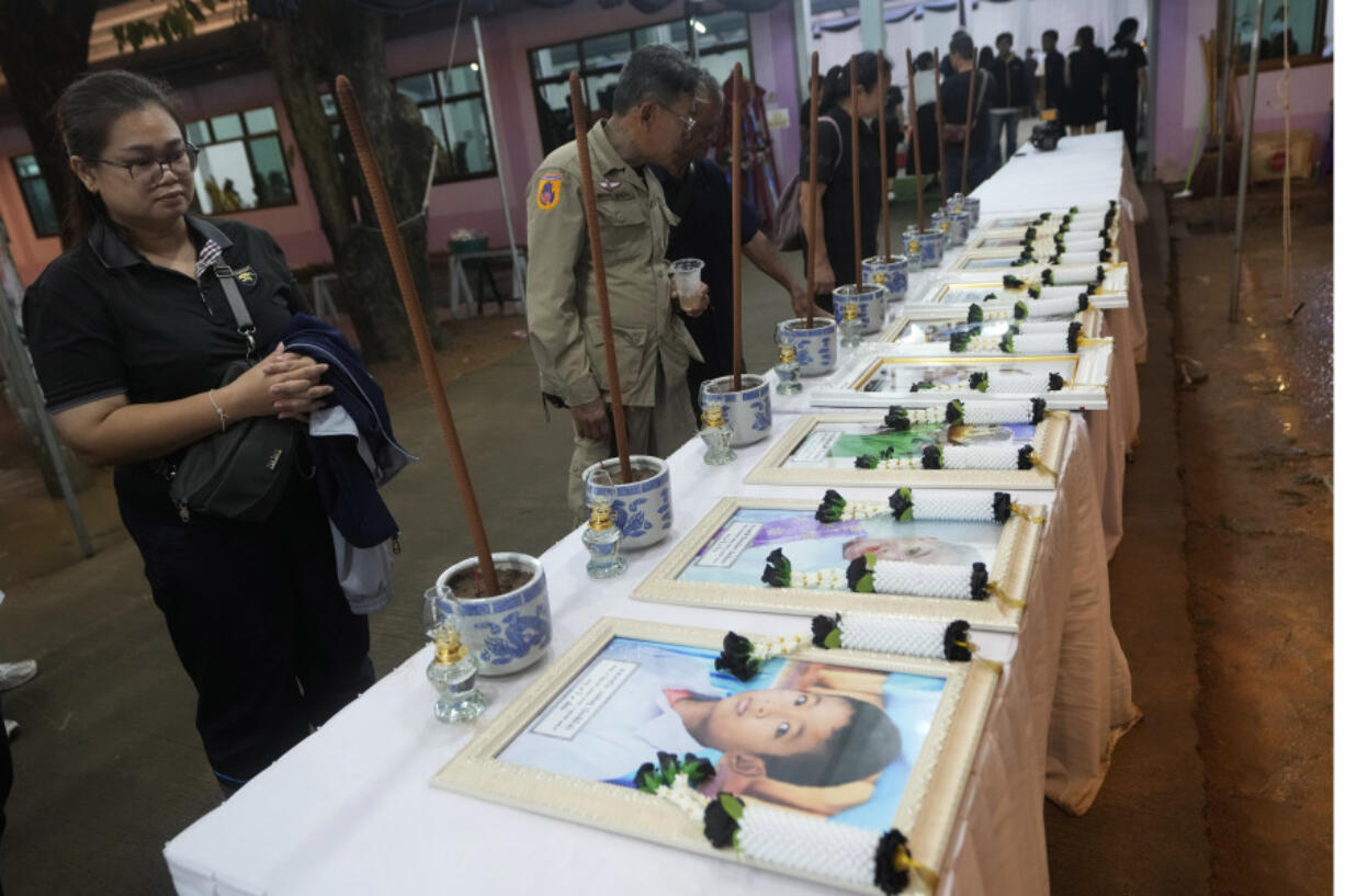 Relatives of the bus fire victims view their portraits at the Wat Khao Phraya Sangkharam School Lan Sak, Uthai Thani province, Thailand, Wednesday, Oct. 2, 2024.