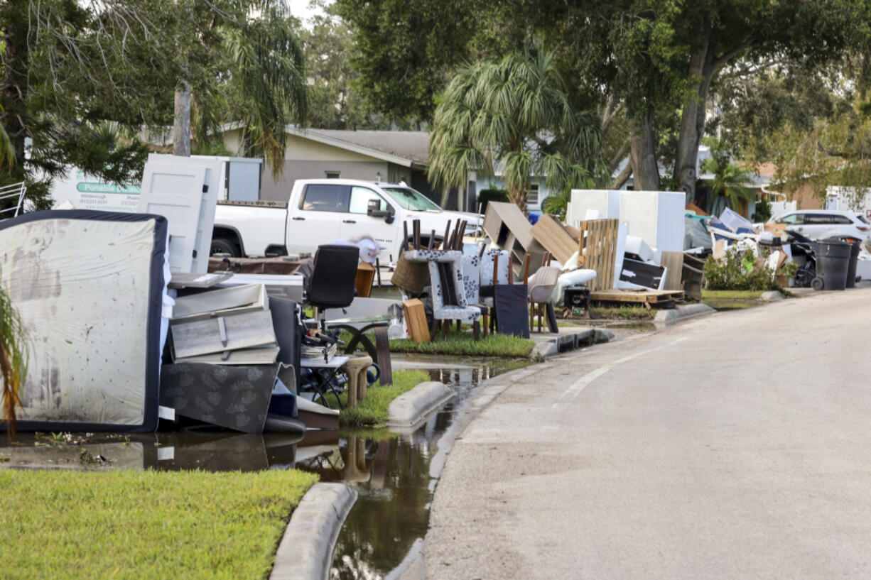 Residents discard items from their homes which filled with floodwaters from Hurricane Helene in the Shore Acres neighborhood on Saturday, Sept. 28, 2024, in St. Petersburg, Fla.