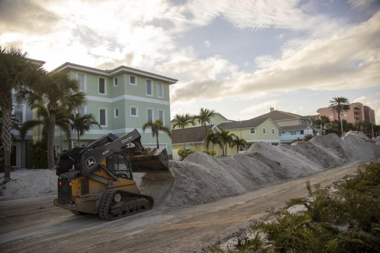 Crews work to clean up the tons of sand and debris pushed onto Gulf Boulevard from Hurricane Helene storm surge, Saturday, Sept. 28, 2024, in Indian Shores, Fla.