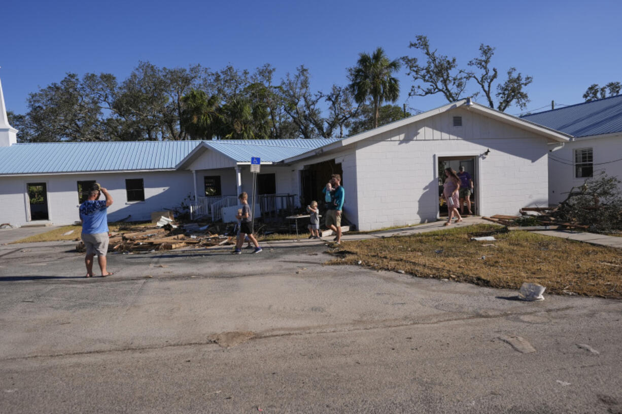 A group from St. Augustine, Fla., who did not want to give their name, that came to help storm victims, arrive to pray outside the damaged First Baptist Church in the aftermath of Hurricane Helene, in Horseshoe Beach, Fla., Sunday, Sept. 29, 2024.