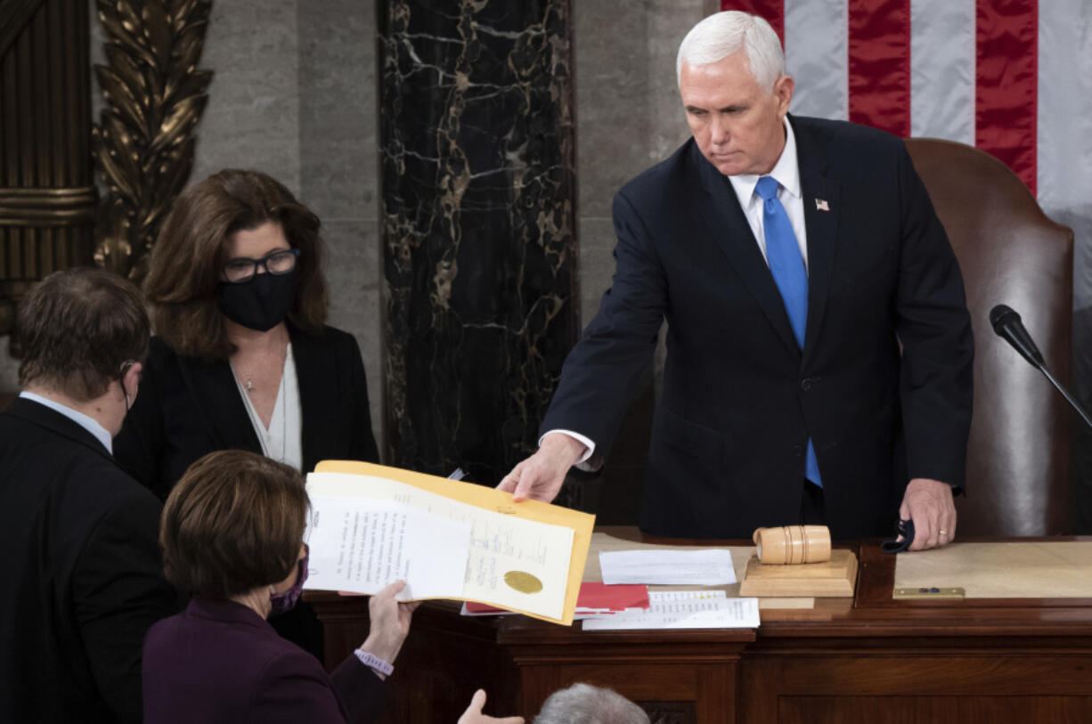 FILE - Vice President Mike Pence hands the electoral certificate from the state of Arizona to Sen. Amy Klobuchar, D-Minn., as he presides over a joint session of Congress as it convenes to count the Electoral College votes cast in November&rsquo;s election, at the Capitol in Washington, Jan. 6, 2021.