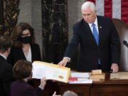 FILE - Vice President Mike Pence hands the electoral certificate from the state of Arizona to Sen. Amy Klobuchar, D-Minn., as he presides over a joint session of Congress as it convenes to count the Electoral College votes cast in November&rsquo;s election, at the Capitol in Washington, Jan. 6, 2021.