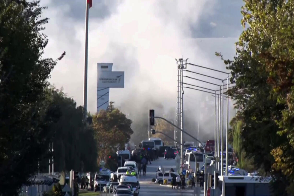 Smoke raises as emergency rescue teams and police officers attend outside Turkish Aerospace Industries Inc. on the outskirts of Ankara, Turkey, Wednesday, Oct. 23, 2024.