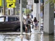 FILE - Mica Martell, left, and his niece and nephews ride bicycles through a flooded neighborhood, Sept. 27, 2024, in Crystal River, Fla. (AP Photo/Phelan M.